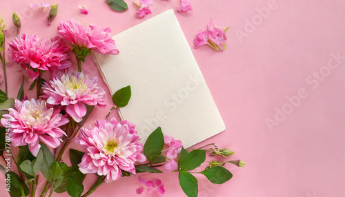 Mock up of white blank paper card and beautiful pink flowers. Spring bouquet on table. Flat lay