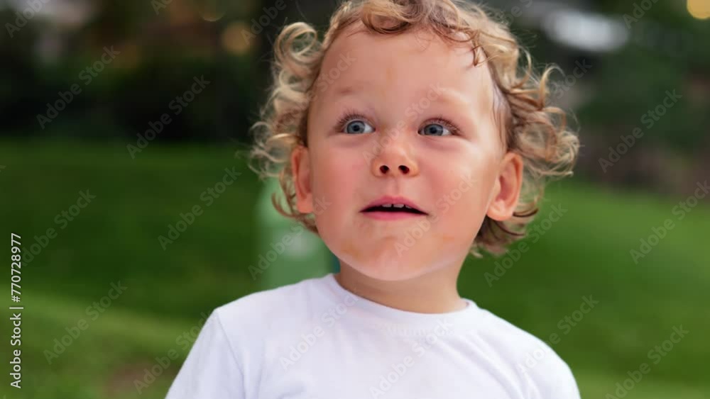 Little boy engages in lively conversation, explaining something to adults with one waiving gesture at end. With curly locks and beautiful eyes shining, he speaks with genuine emotion and enthusiasm,
