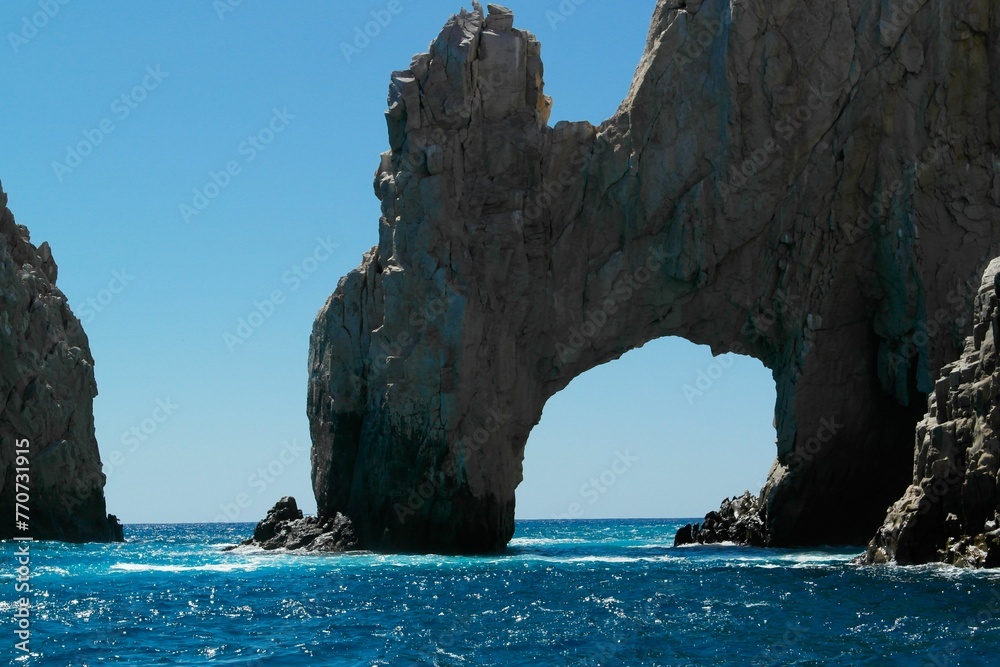 Scenic vista of two large rocks and two archways emerging from the calm water
