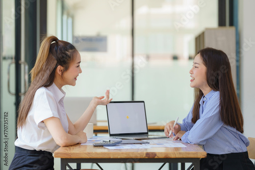Two Asian businesswomen discuss new startup project idea presentation and analyze planning and financial statistics and investment market at the office.