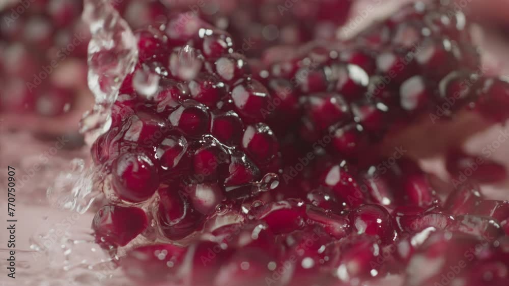 Drops of water dripping onto a pomegranate in slow motion in macro. Red garnet seeds close up Drops of water dripping onto a pomegranate in slow motion in macro. Red garnet seeds close up