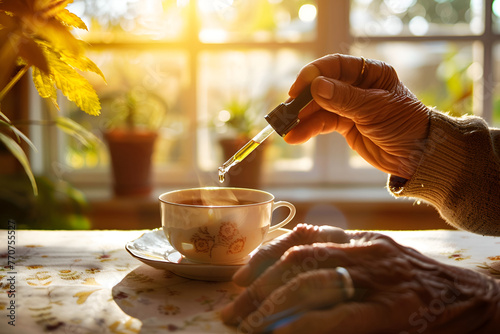 Elderly hand adding CBD oil to tea, a morning routine in warm sunlight. photo