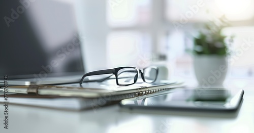 Close-Up View of Stacked Laptop, Glasses, Notepad, and Smartphone