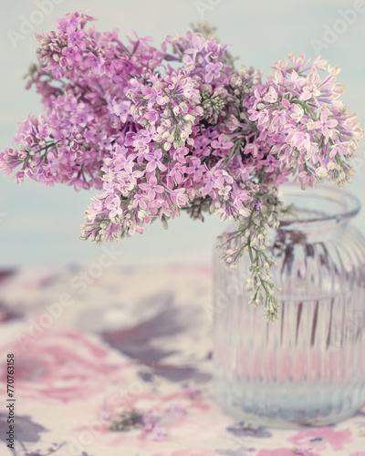 A beautiful  lilac in a vase on a table. Blue background.Pastel tonality and soft focus.
