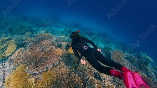 Freediving on the abundant healthy reef. Woman freediver glides underwater and watches the healthy coral reef in the Komodo National Park in Indonesia © Dudarev Mikhail
