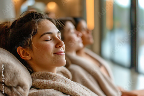Three women in robes peacefully recline in a relaxation room, indulging in the serene atmosphere of a spa retreat. photo