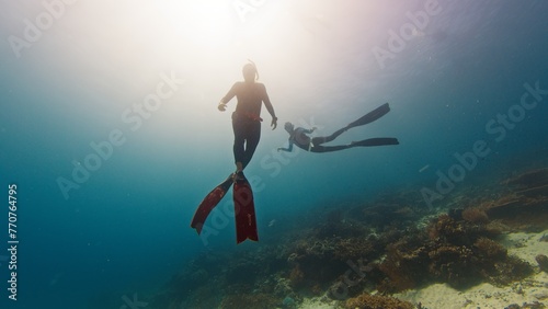 Two male freedivers swim underwater and explores vivid and healthy coral reef in Komodo National Park in Indonesia