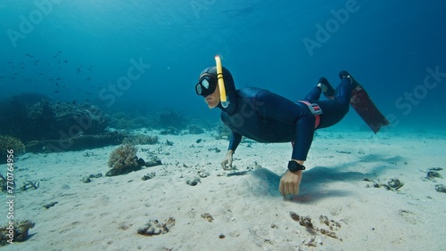 Male freediver glides in the tropical sea over the sandy bottom