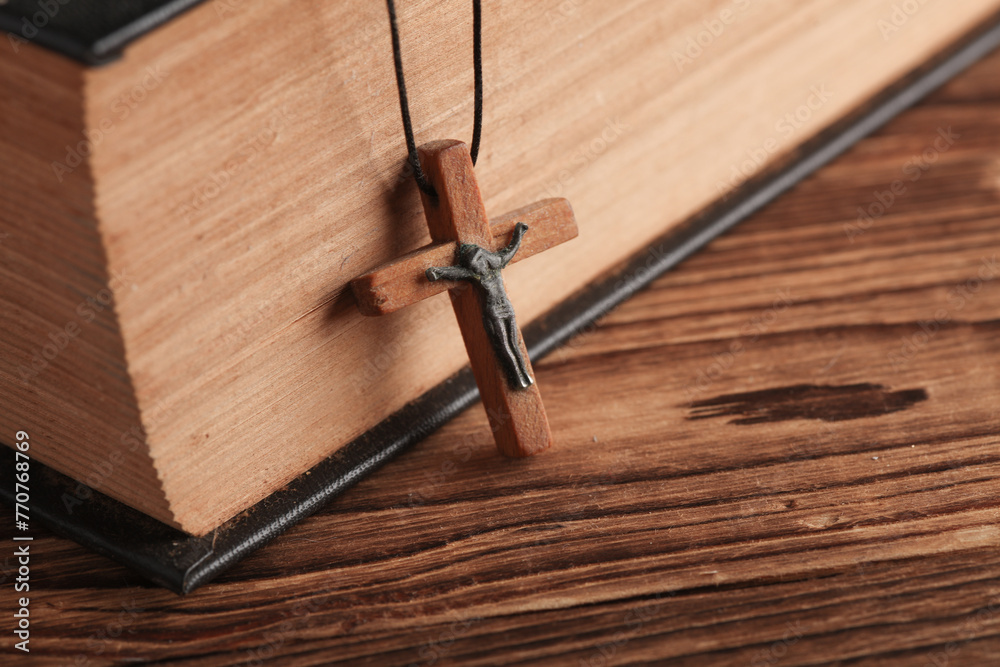 Obraz premium Bible book and wooden Christian cross on a string, wooden table