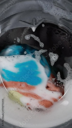 Washing Colored Laundry In A Washing Machine, Spinning Colorful Items Through A Glass Door.