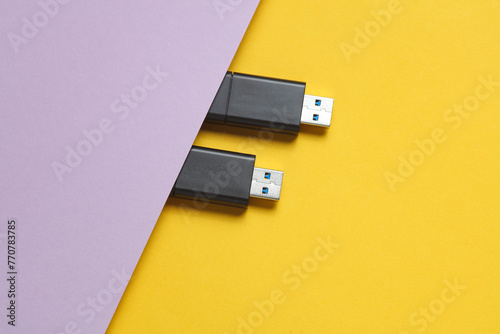 Two black USB flash drives on purple yellow background photo