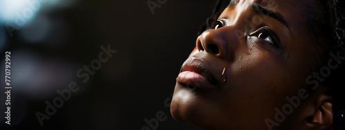Young black woman looking up praying to God with tears in eyes, being touched by His Grace. Christian and faith concept. photo