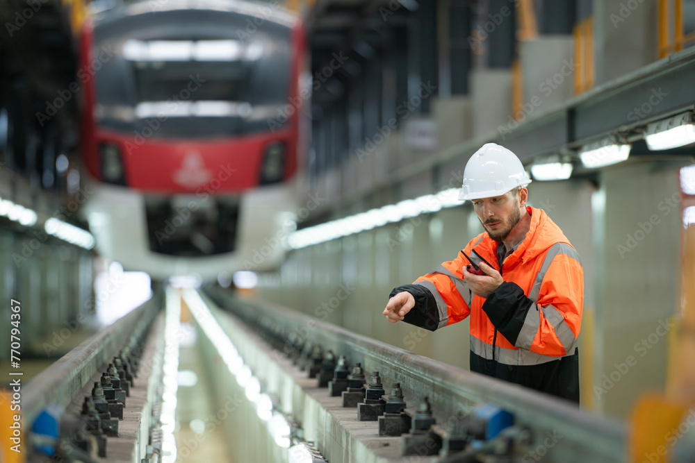 Portrait of a young male technician using a walkie talkie working and standing in a skytrain repair station. Portrait of a young male technician using a walkie talkie working and standing in a skytrain repair station.