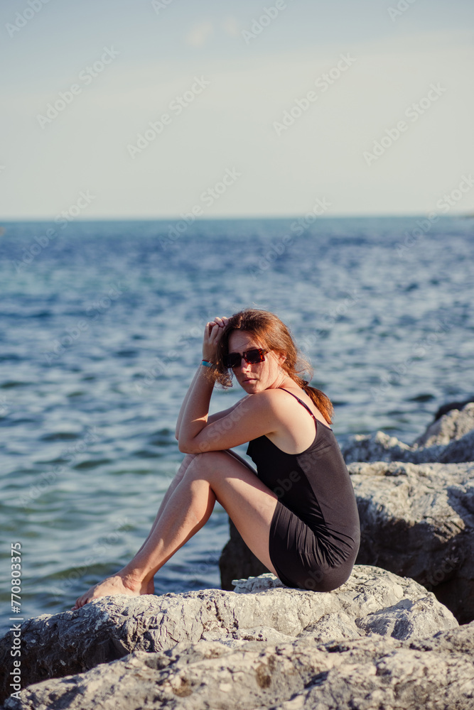 A young beautiful girl posing against the background of the sea A young beautiful girl posing against the background of the sea