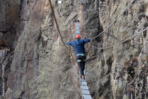 Man in body harnesses feature life-safety, attaches hooks to iron brackets, climbs rock, active lifestyle of people, mountaineering, viaferrata in mountains of pyrenees, High quality photo photo