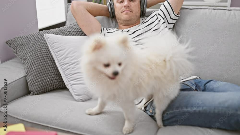 At home, handsome young caucasian man and his puppy, immersed in music, sit on the sofa with headphones on - a net slice-of-life moment filled with relaxation, tech savvy, and canine love At home, handsome young caucasian man and his puppy, immersed in music, sit on the sofa with headphones on - a net slice-of-life moment filled with relaxation, tech savvy, and canine love