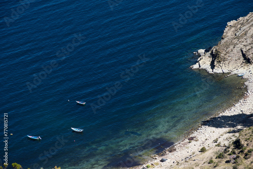 Three boats anchored near a small strip of sand on the Sun Island in Bolivia