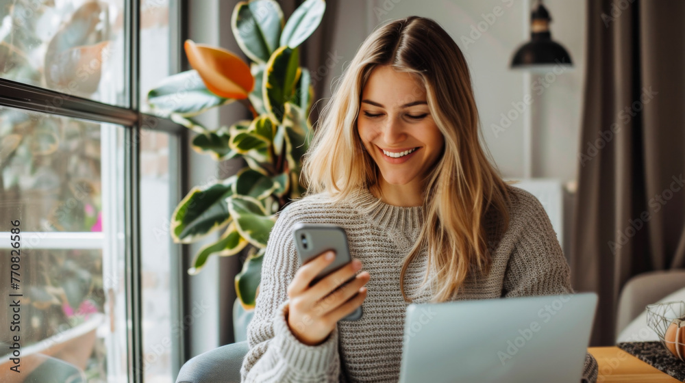 Smiling woman using smartphone with laptop on a cozy indoor setting Smiling woman using smartphone with laptop on a cozy indoor setting
