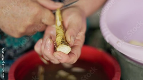 grandma peeling horseradish with a kitchen knife, closeup with slow motion photo