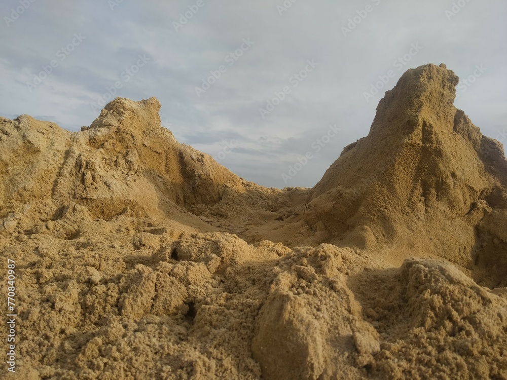 A pile of sand that looks like a mountain reaching high into the sky.