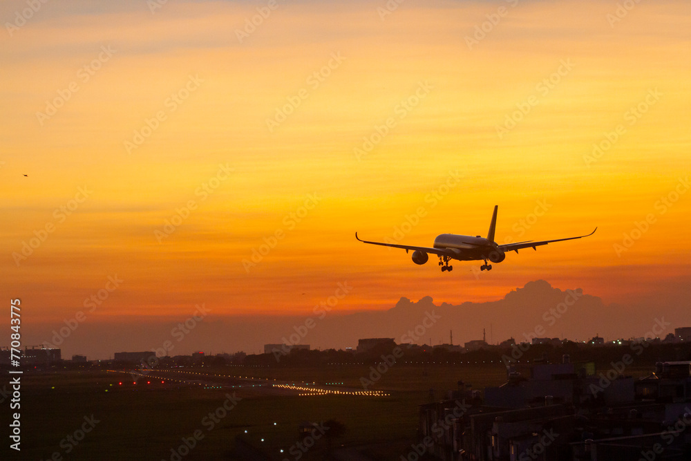 An Commercial Airplane Landing At Sunset.