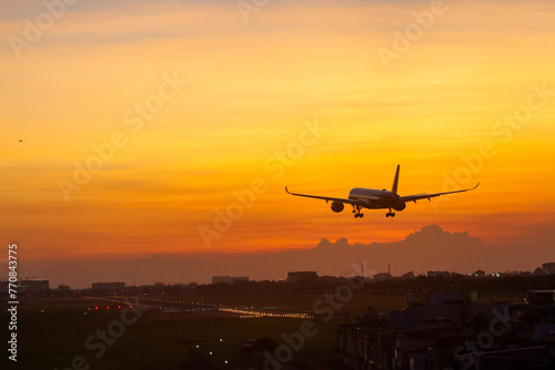 An Commercial Airplane Landing At Sunset.