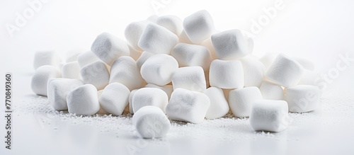 A cluster of fluffy white marshmallows displayed on a sleek white surface. This minimalist composition creates an elegant circle of softness, perfect for a macro photography session