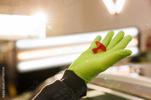 Mechanic with green gloves holds a pin for car dent removal