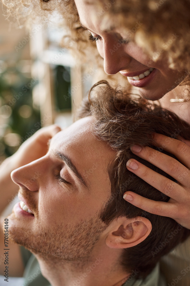 Closeup of curly young woman gently massaging boyfriends head smiling together Closeup of curly young woman gently massaging boyfriends head smiling together