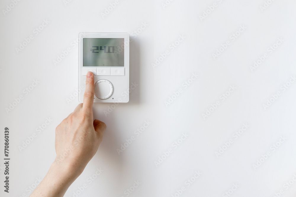 Cropped shot of woman hand setting room temperature on thermostat at home Cropped shot of woman hand setting room temperature on thermostat at home