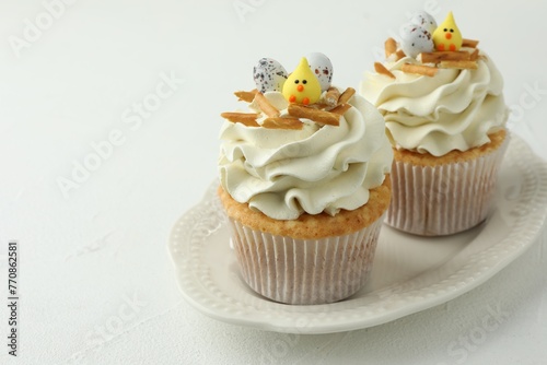 Tasty Easter cupcakes with vanilla cream on white table, closeup. Space for text
