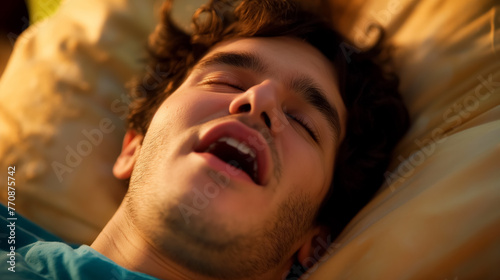 A close-up portrait of a young man, comfortably snoring in deep sleep, mouth open and completely relaxed. photo