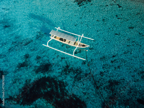 Fishing boat at anchor in blue ocean on tropical island. Aerial view.