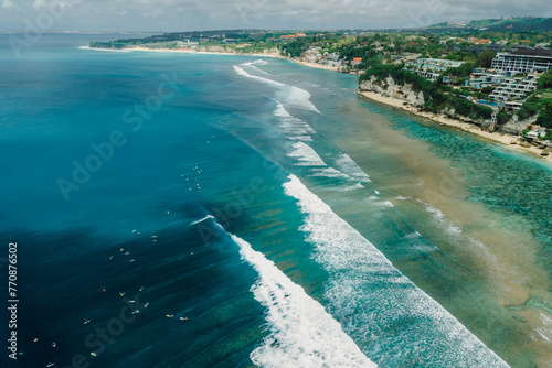 Drone view with ocean coastline and perfect long waves with surfers.