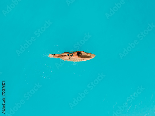 Surf girl relaxing on surfboard in ocean. Aerial view of woman during surfing