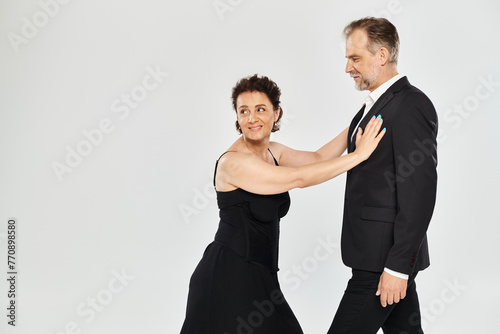 Side view shot of mature attractive smiling couple in a tango dance pose isolated on grey background