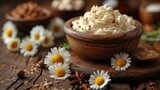   A wooden table holds a bowl filled with whipped cream Surrounding it are daisies Nearby, other bowls of food rest on the table
