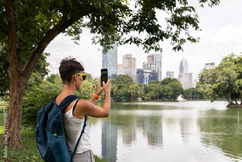 Woman taking a photo with her mobile phone in Lumpenee Park Bangkok