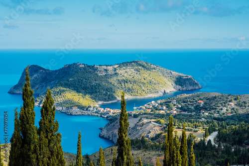 Above view to Assos village and beautiful blue sea. Cypress trees stands out in foreground. Kefalonia island, Greece