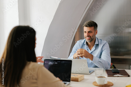 Happy businessman discussing in the office with his female colle photo