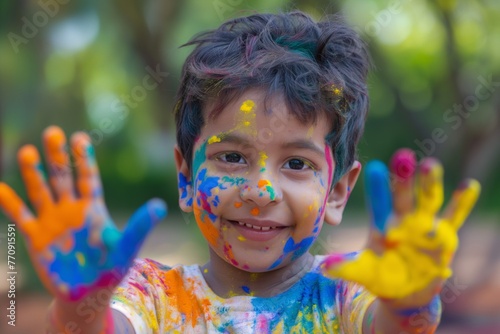 A cute little smiling boy shows his painted hands to the camera during the Indian festival Holi