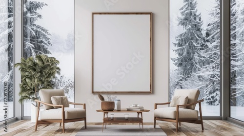 An empty rectangle frame mockup in oak wood, placed on the wall of a living room with two armchairs facing each other and a coffee table between them. A large window showing a snowy landscape outside photo