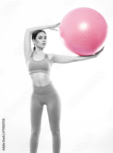 Slim, bodybuilder girl in a lilac tracksuit, sitting on a mat with a Pilates ball,  cardio workout. Sports concept, fat burning and healthy lifestyle. © Dimid