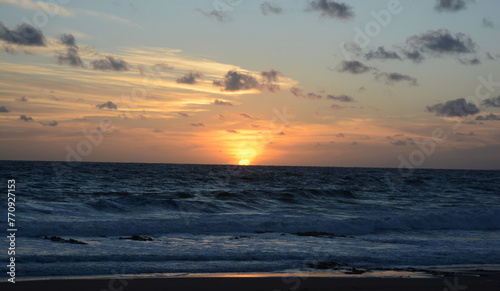 sunset at sea  with orange sky and the sun setting on the beach horizon