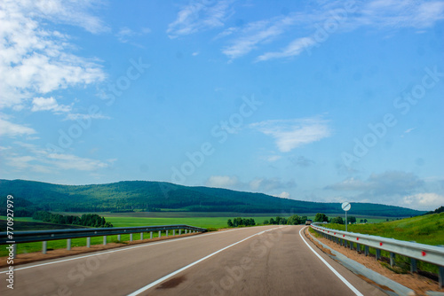 A road leading into the distance. Road against the background of a blue sky with clouds. beautiful landscapes with mountains