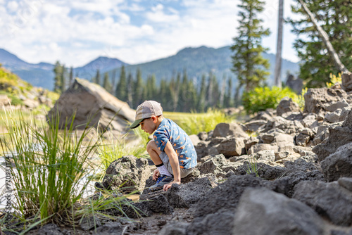 child exploring on rocks near a lake 