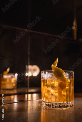 Yellow alcoholic cocktail with ice and lemon zest on a background of a concrete surface