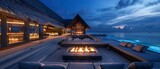 Maldives night haven: Firelit seating seating area oasis with a large fire pit and comfortable loungers amidst modern architectural design luxury villa