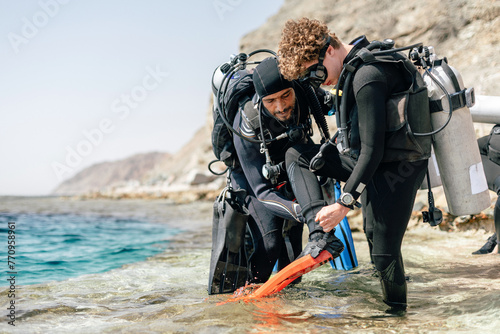 Scuba Diving Instructor Assisting Student to putting on Finns
