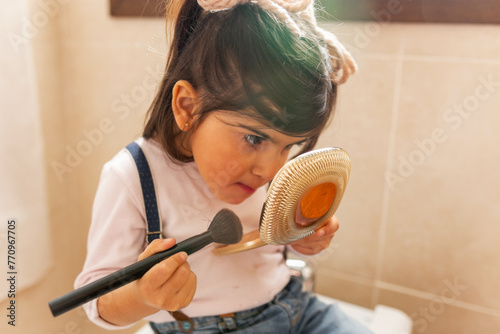 little girl putting on makeup in the bathroom at home